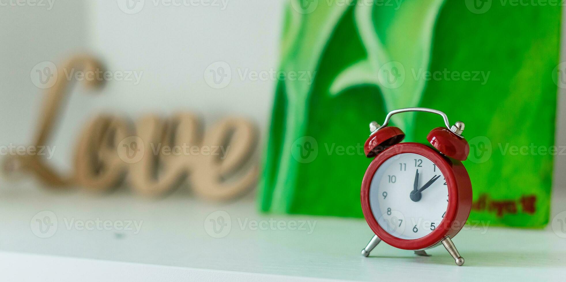 Red old retro style alarm clock on wood table. Alarm clock shows eight oclock photo