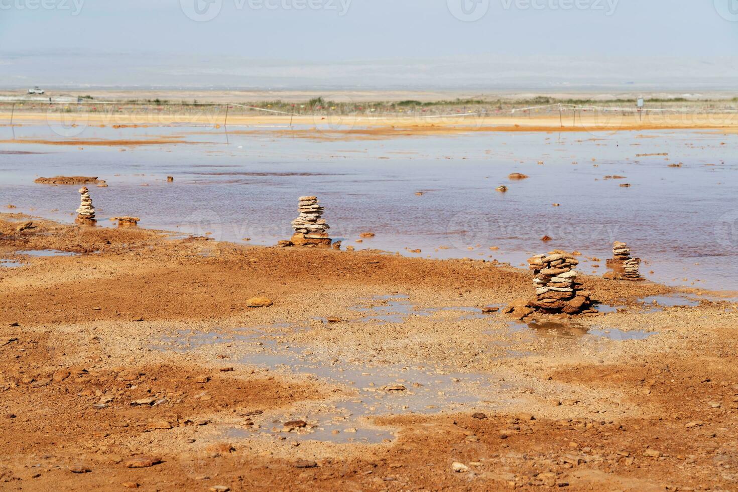 Muddy ground with spring water, with stacks of stones on one side. photo