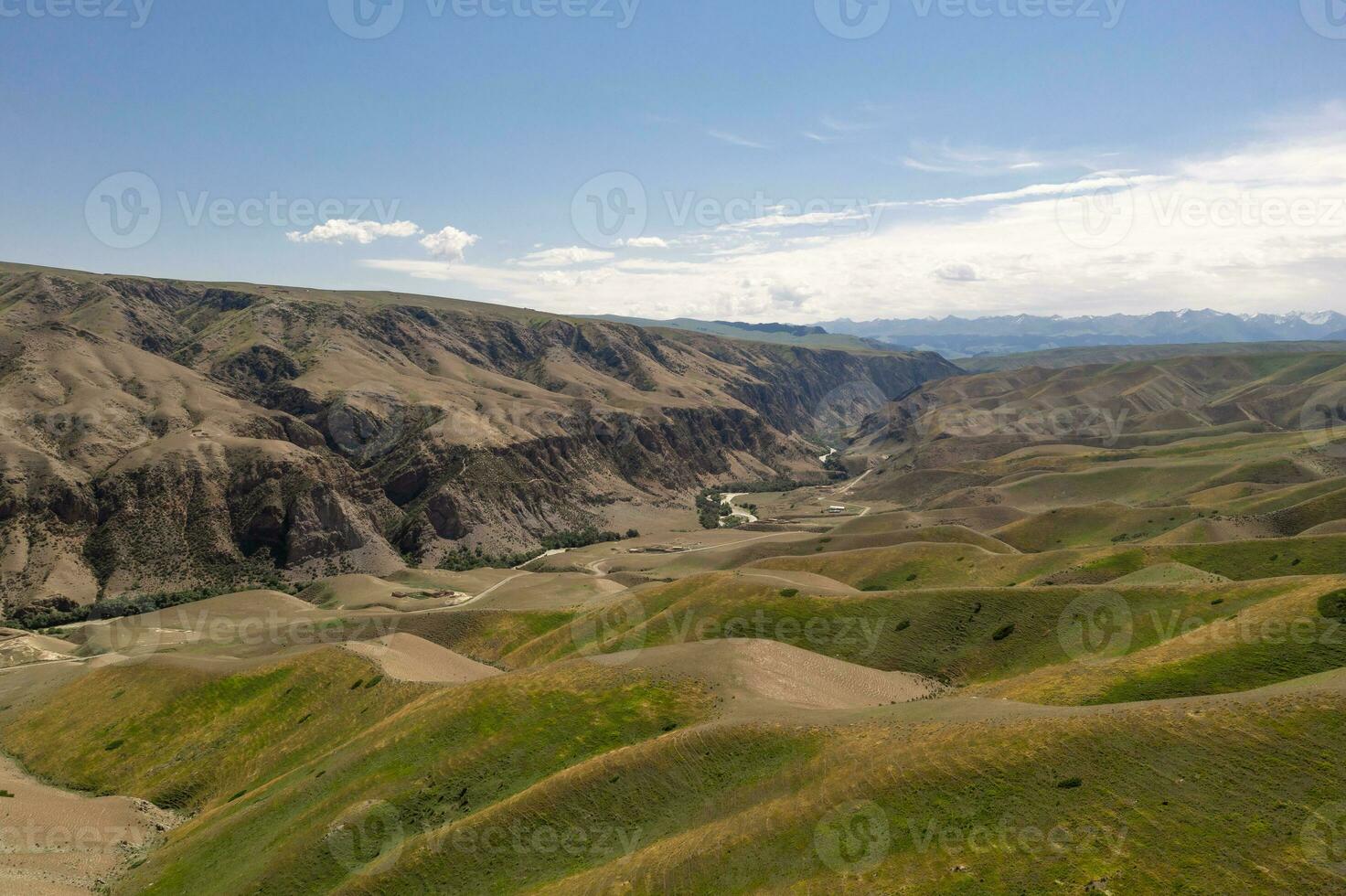 Mountain peaks and grassland are under white clouds. photo