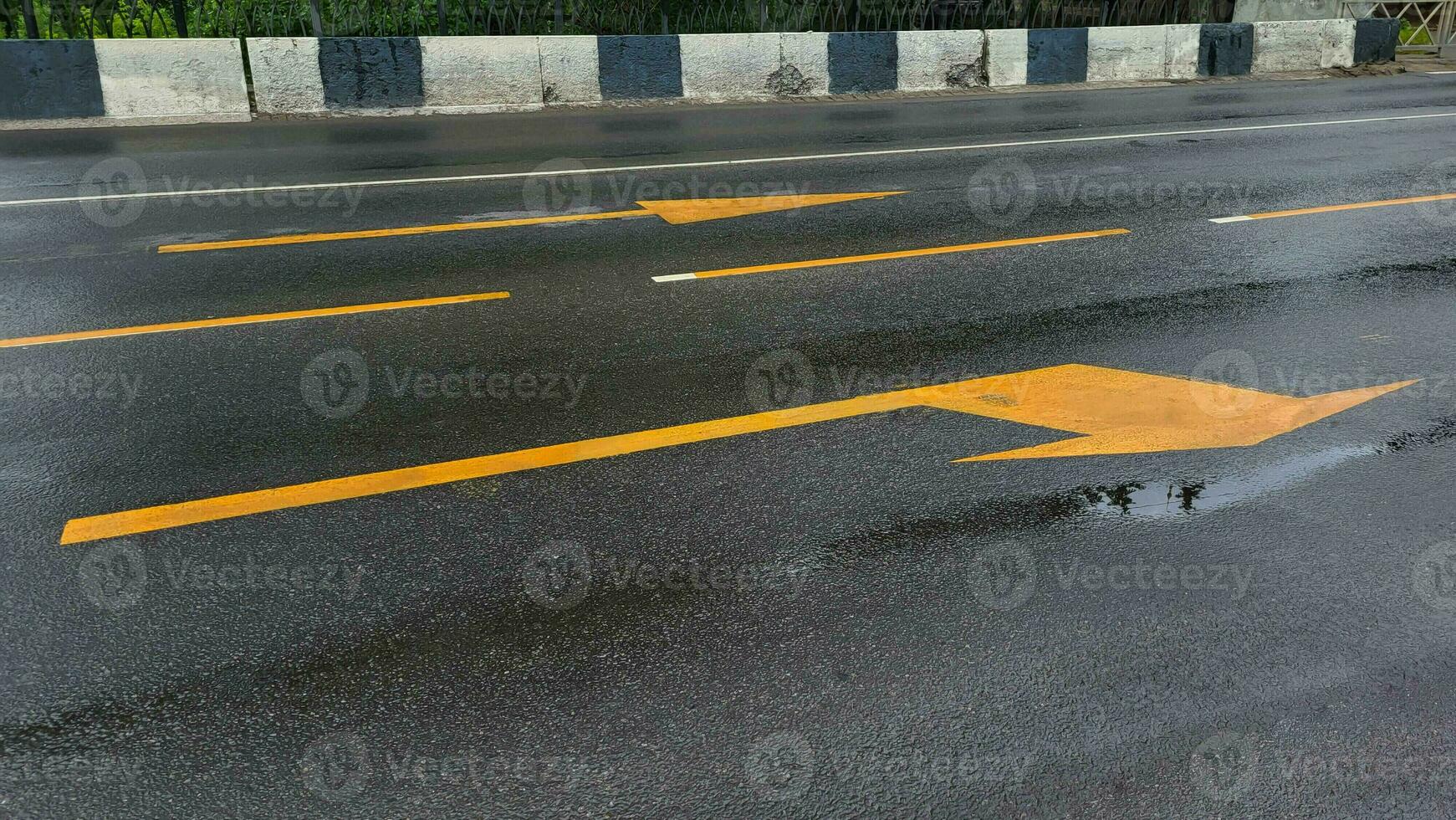 Yellow arrows of road markings in rainy weather. photo