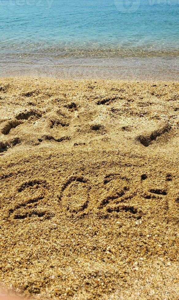 The numbers 2024 are written on the sandy beach. The concept of the new year photo