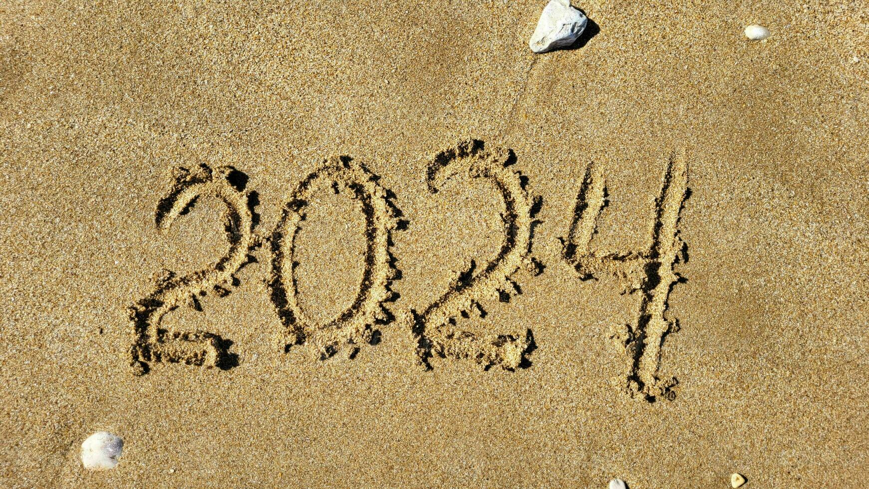 The numbers 2024 are written on the sandy beach. The concept of the new year photo