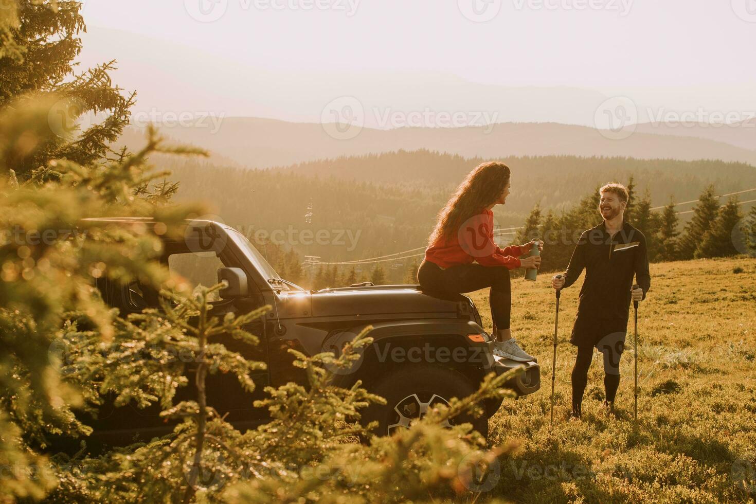 Young couple relaxing by a terrain vehicle hood at countryside photo