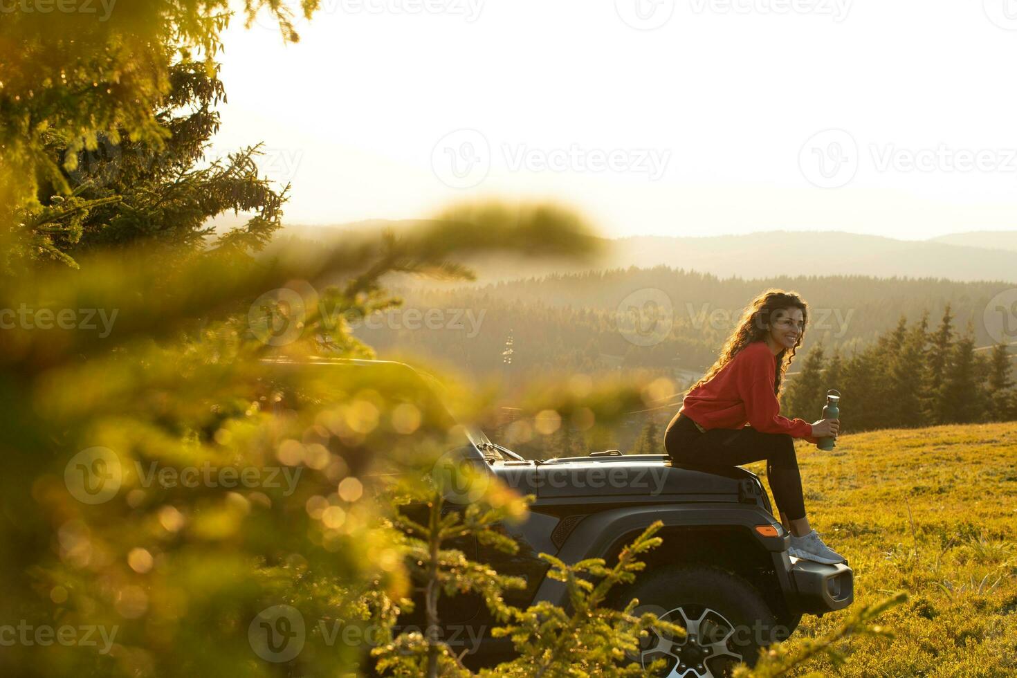 Young woman relaxing on a terrain vehicle hood at countryside photo