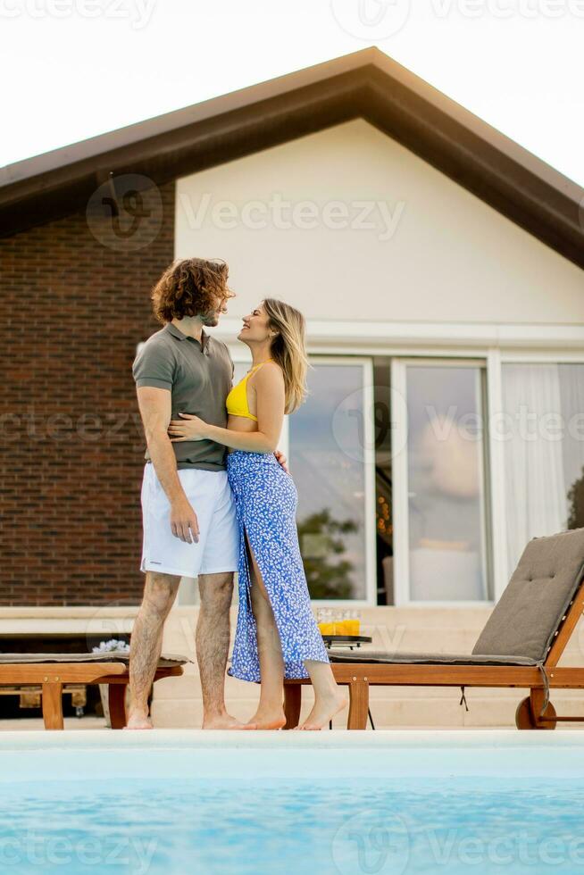 Young couple relaxing by the swimming pool in the house backyard photo