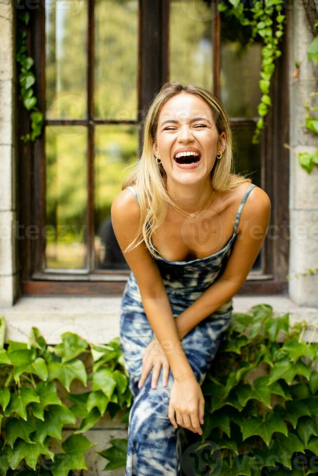 bonito joven mujer por el antiguo casa con hiedra foto