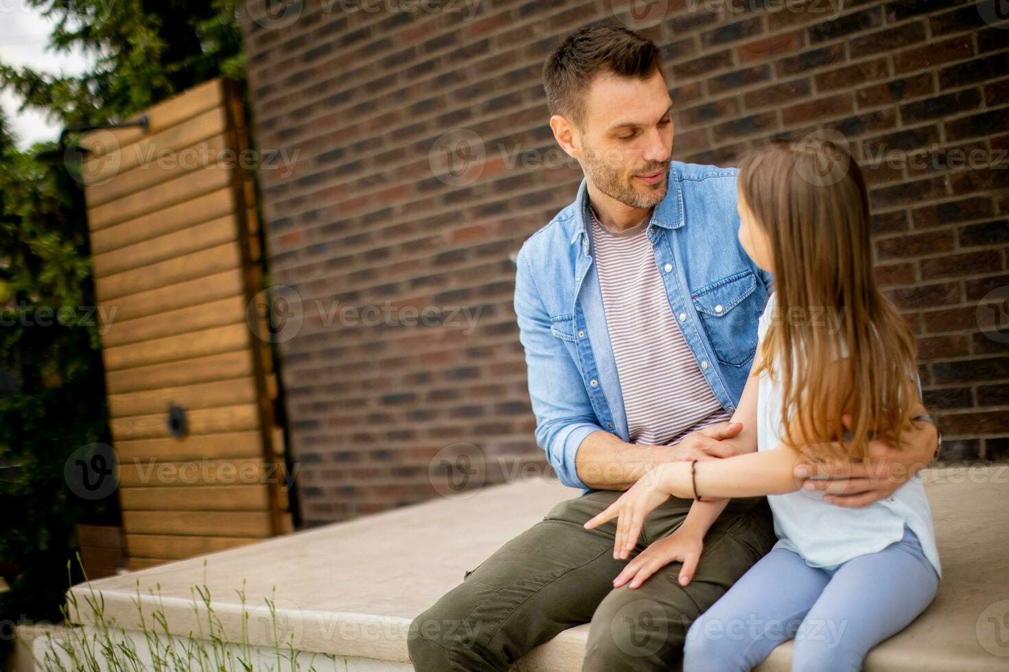 Father and his daughter have a good time in front of house door photo