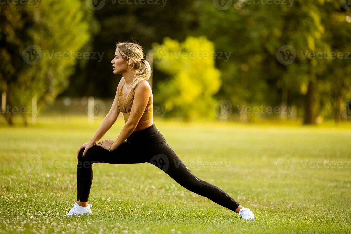 bonito joven mujer extensión en el parque foto