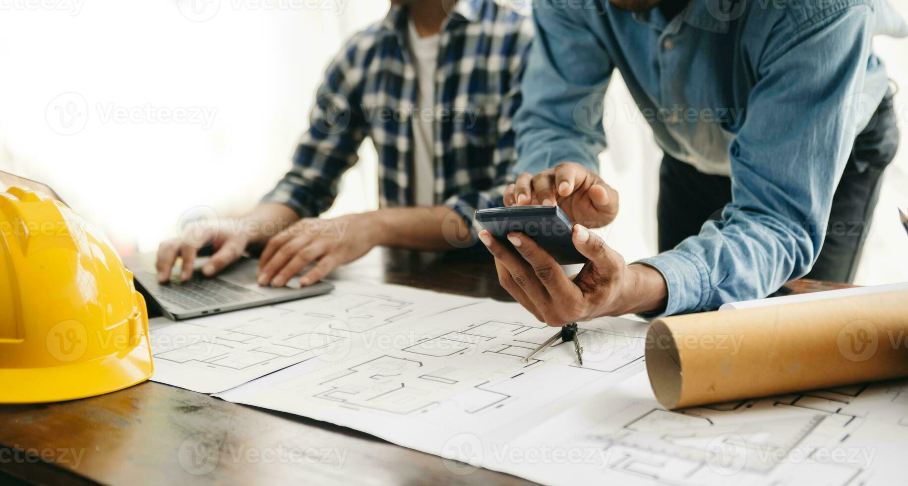 Two colleagues discussing data working and tablet, laptop with on architectural project at construction site at desk photo