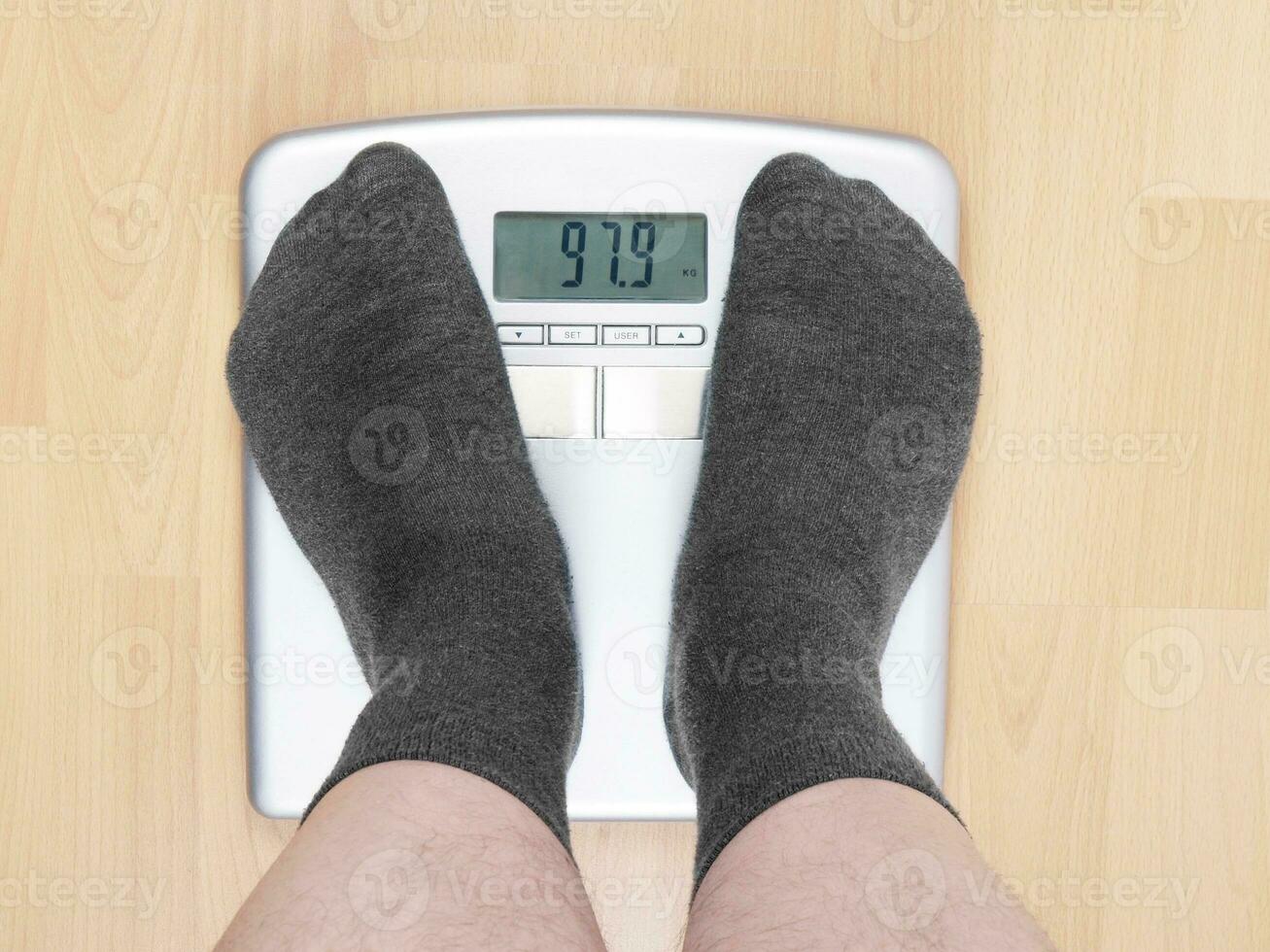 overweight man in socks standing on scales photo