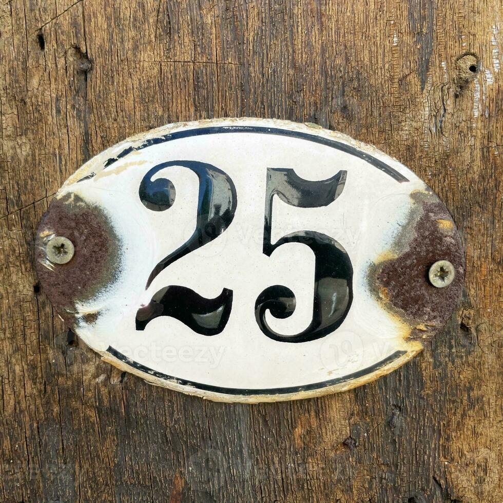 old rusty house number twenty-five 25 plaque on wall photo