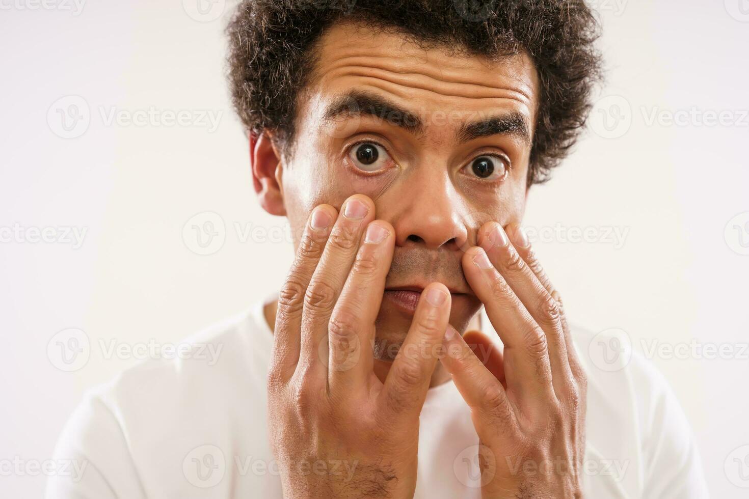 cansado mezclado carrera adulto hombre es mirando a su ojo bolsas. foto