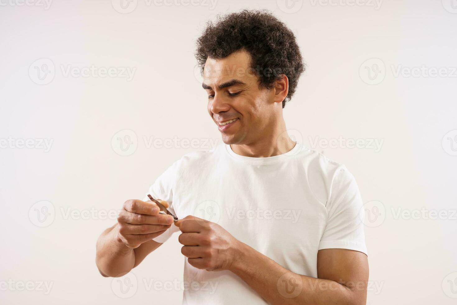 Handsome mixed race adult man is cutting his fingernails. photo