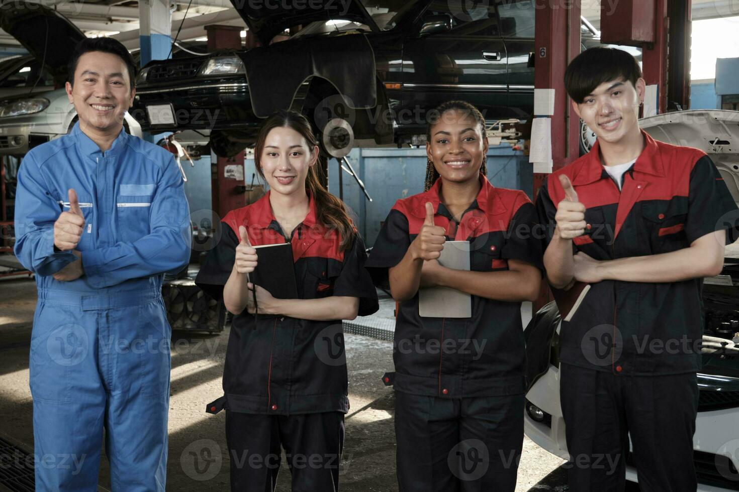 Portrait of multiracial professional mechanic team thumbs up and look at camera, work at car service garage, happy maintenance jobs, check and repair occupation in automotive industry business. photo