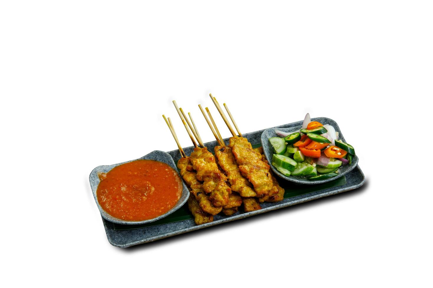 Pork Satay on plate. Grilled pork served with peanut dipping sauce,toasted bread and sweet sour sauce decorated with cucumber,onion and chili. One of the best Thai street food. photo