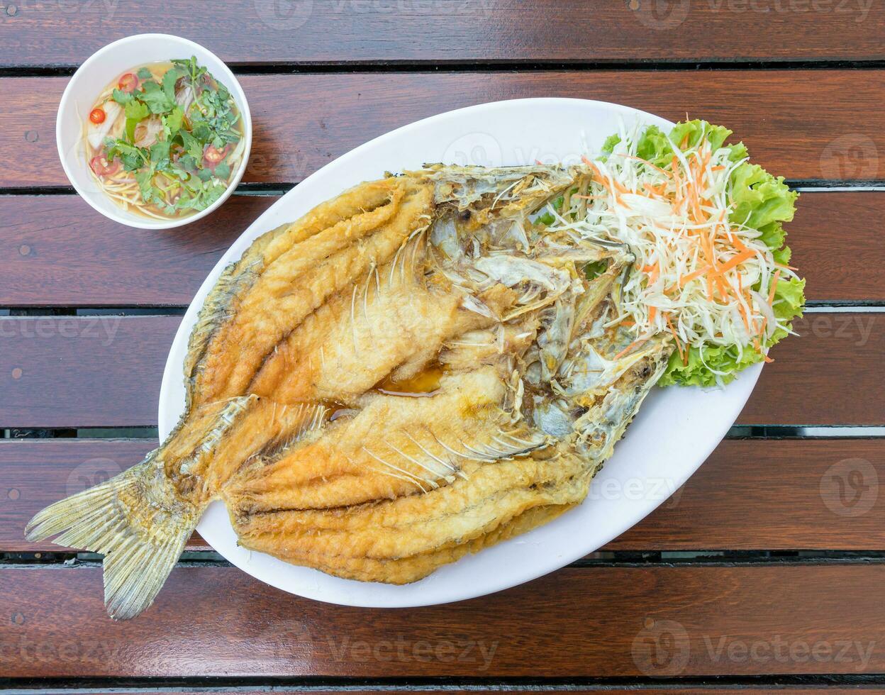 frito pargo pescado blanco en blanco plato en madera mesa servido con pescado salsa y vegetales. foto