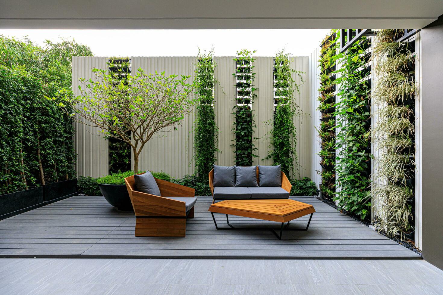two stylish wooden chairs with cushions and a small wooden table at a balcony of a room in a resort, surrounded by garden photo