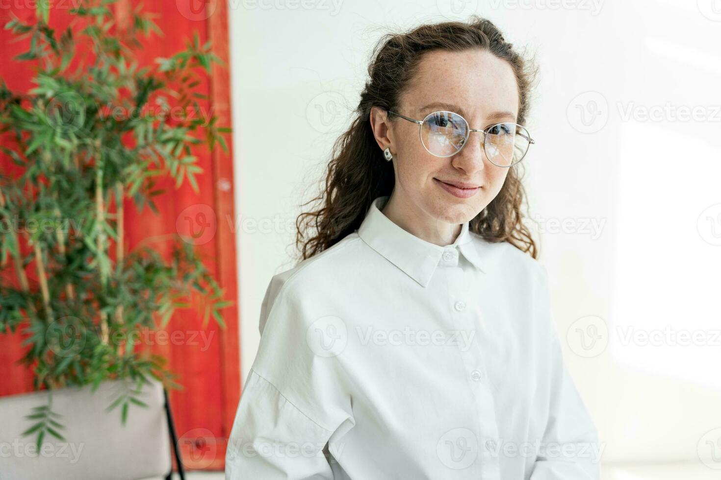 retrato de un mujer con lentes diseñador negocio estilo en el oficina lugar de trabajo. un exitoso gerente mira a el cámara y sonrisas foto