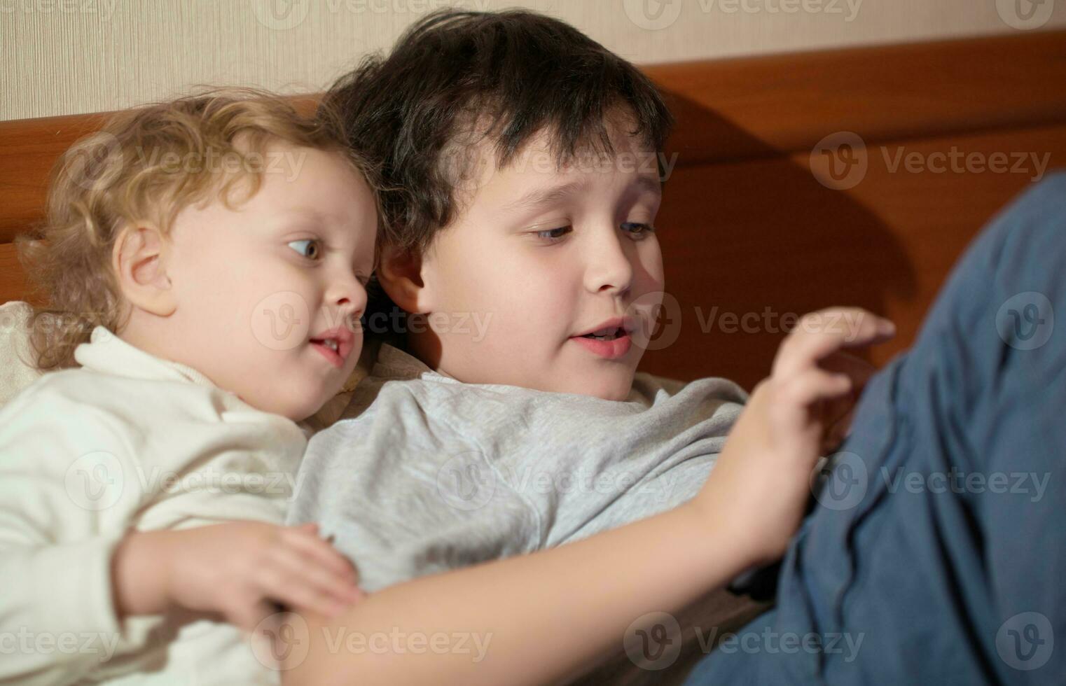 dos joven niños jugando con un tableta foto