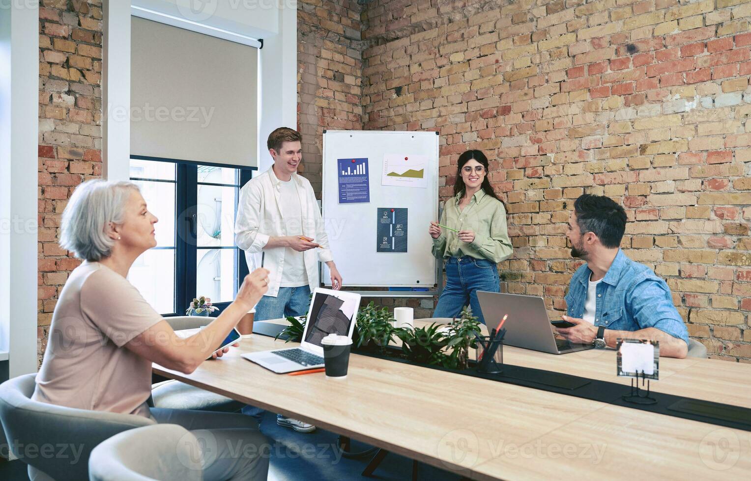 colegas que se discute un nuevo proyecto mientras utilizando rotafolio con gráficos, laptops en moderno oficina. puesta en marcha, trabajo colaborativo, administración concepto foto