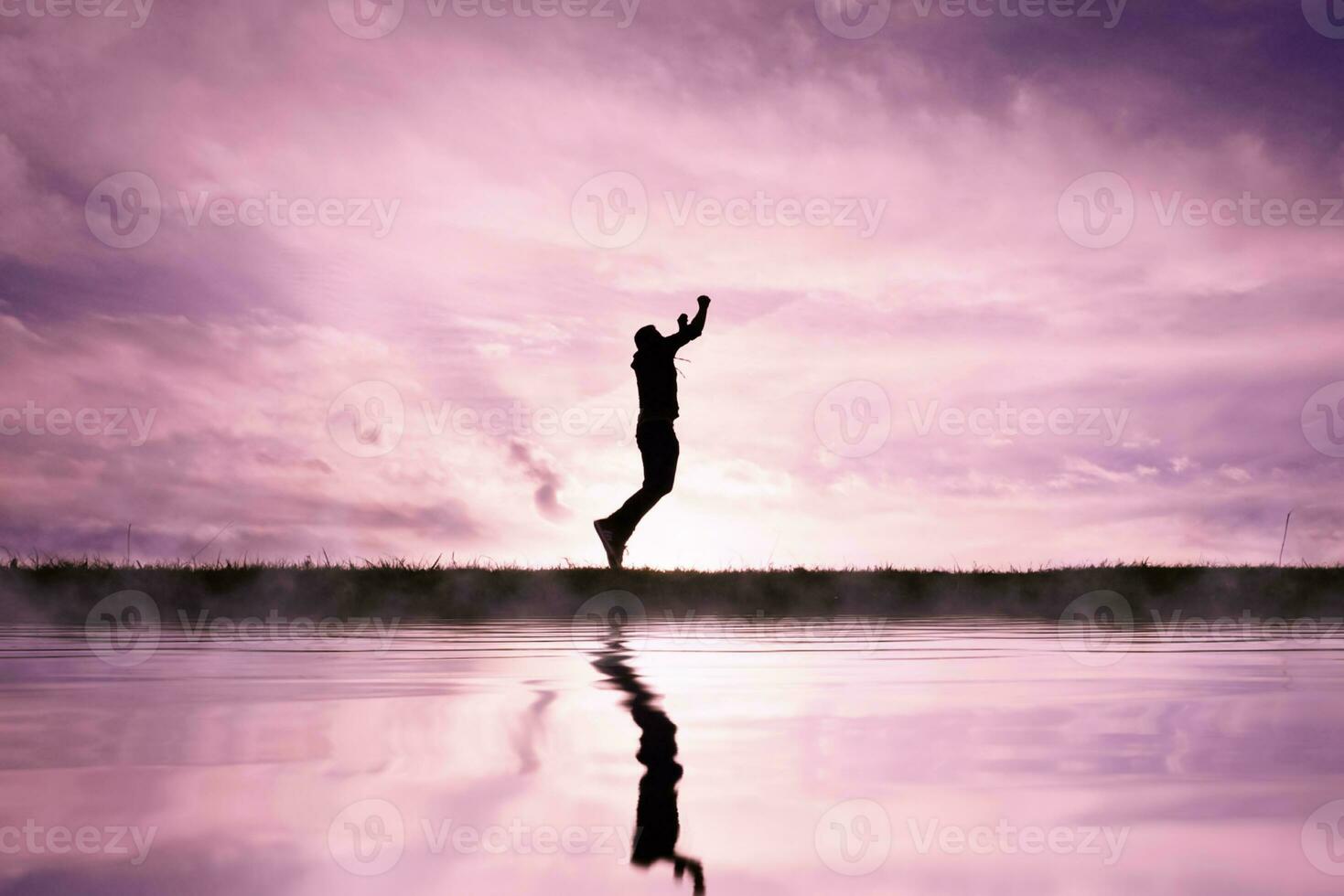 man jumping over a pond with a sunset background photo