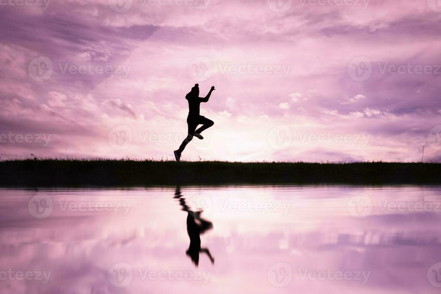 man jumping over a pond with a sunset background photo