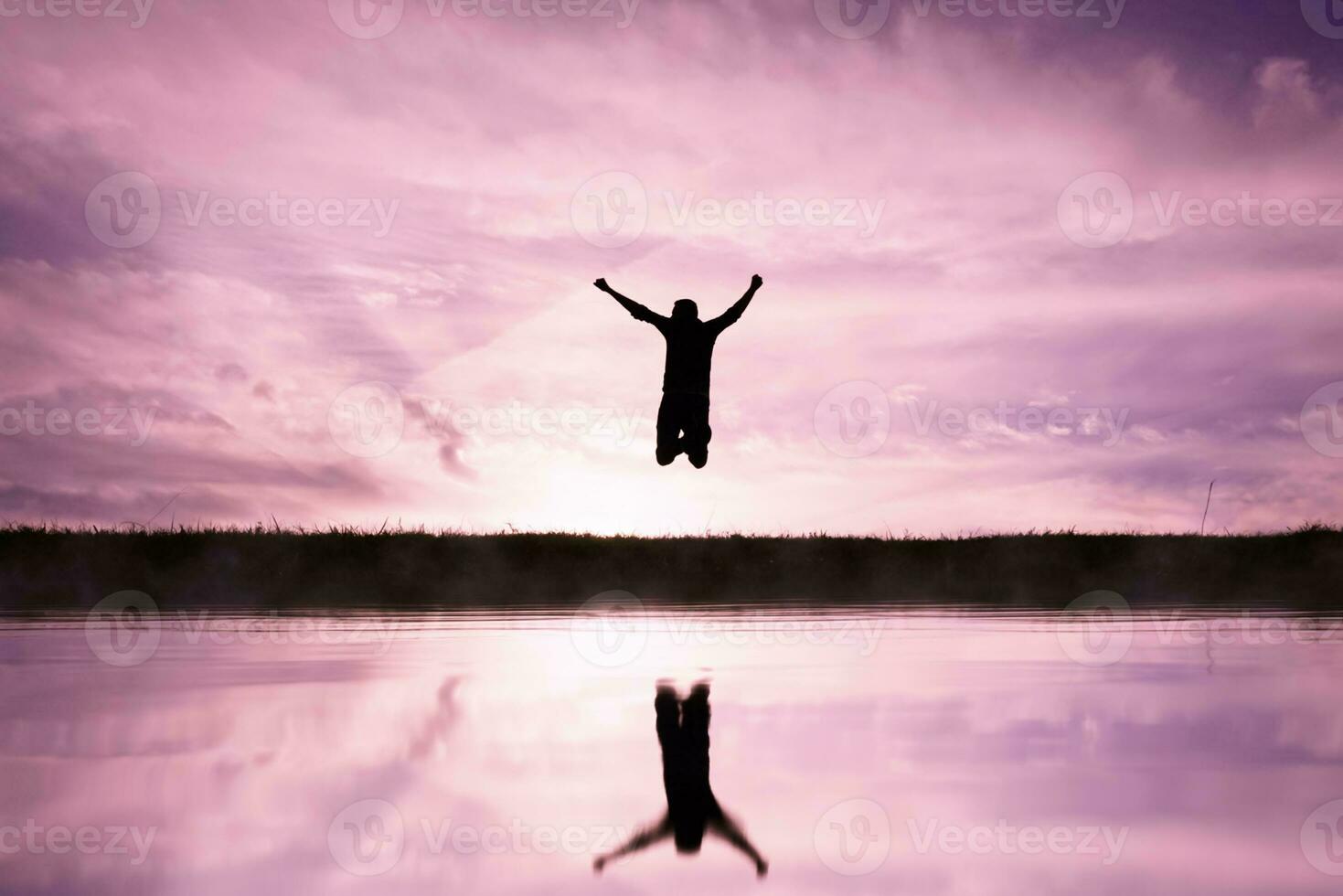 man jumping over a pond with a sunset background photo