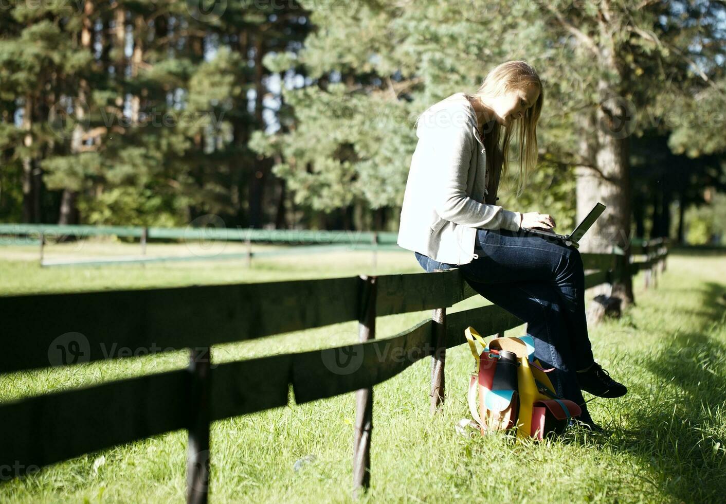 Young woman sitting on a rustic fence photo