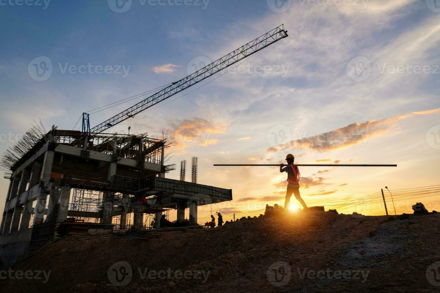 A construction worker in construction site at sunset in evening time. Silhouette of construction. photo