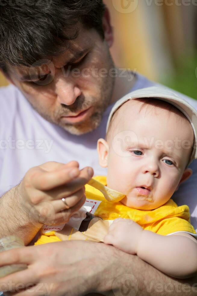 Father trying to feed infant photo