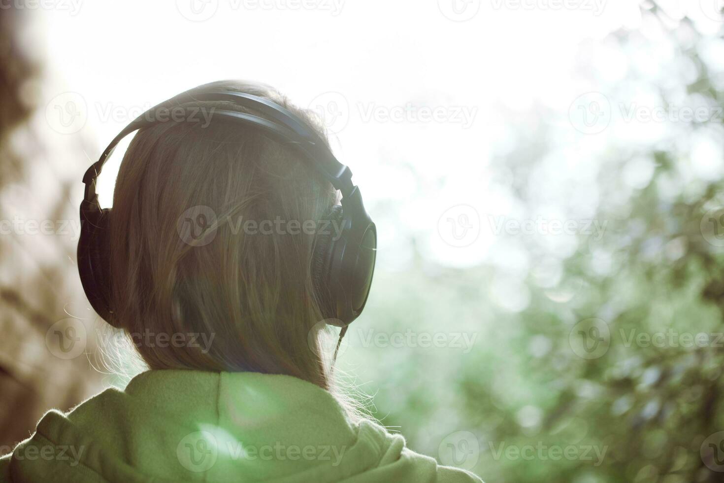 mujer en auriculares contra la luz del sol brillante foto