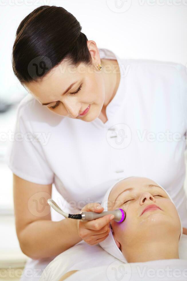 Cosmetician providing lifting procedure with special equipment photo