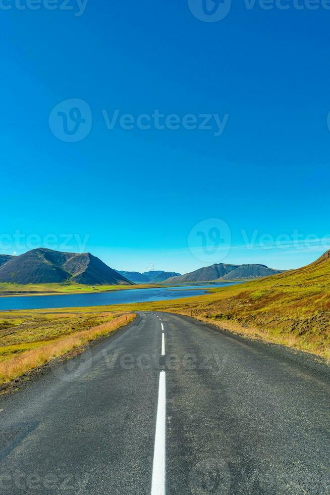 Cover page with a paved road and Icelandic colorful and wild landscape with fjords and sea at summer time, West Iceland photo
