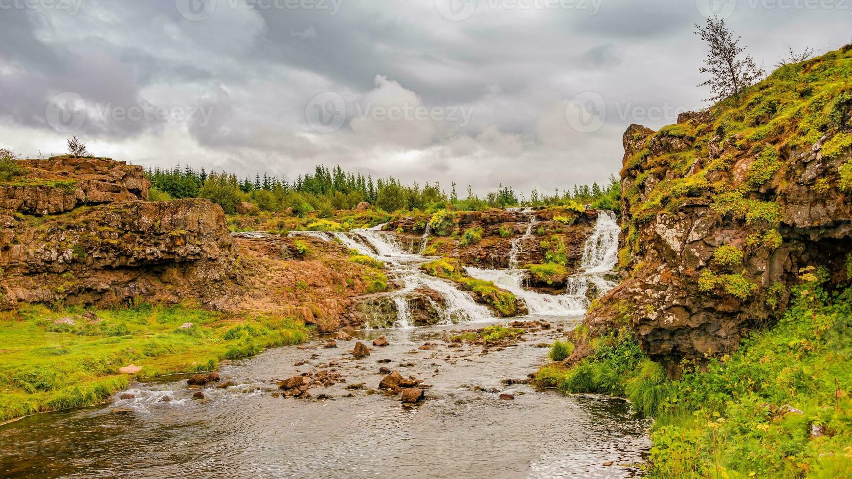 Wonderful waterfal named Kermoafoss in Iceland, in the city park of Reykjavik, in Autumn colors and dramatic sky photo