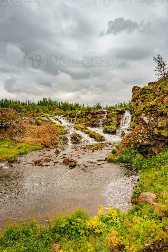 Wonderful waterfall named Kermoafoss in Iceland, in the city park of Reykjavik, in Autumn colors and dramatic sunset sky photo