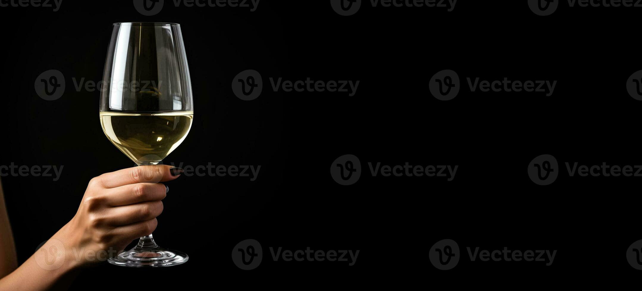 Hand holding a glass of white wine side view isolated on a black background photo