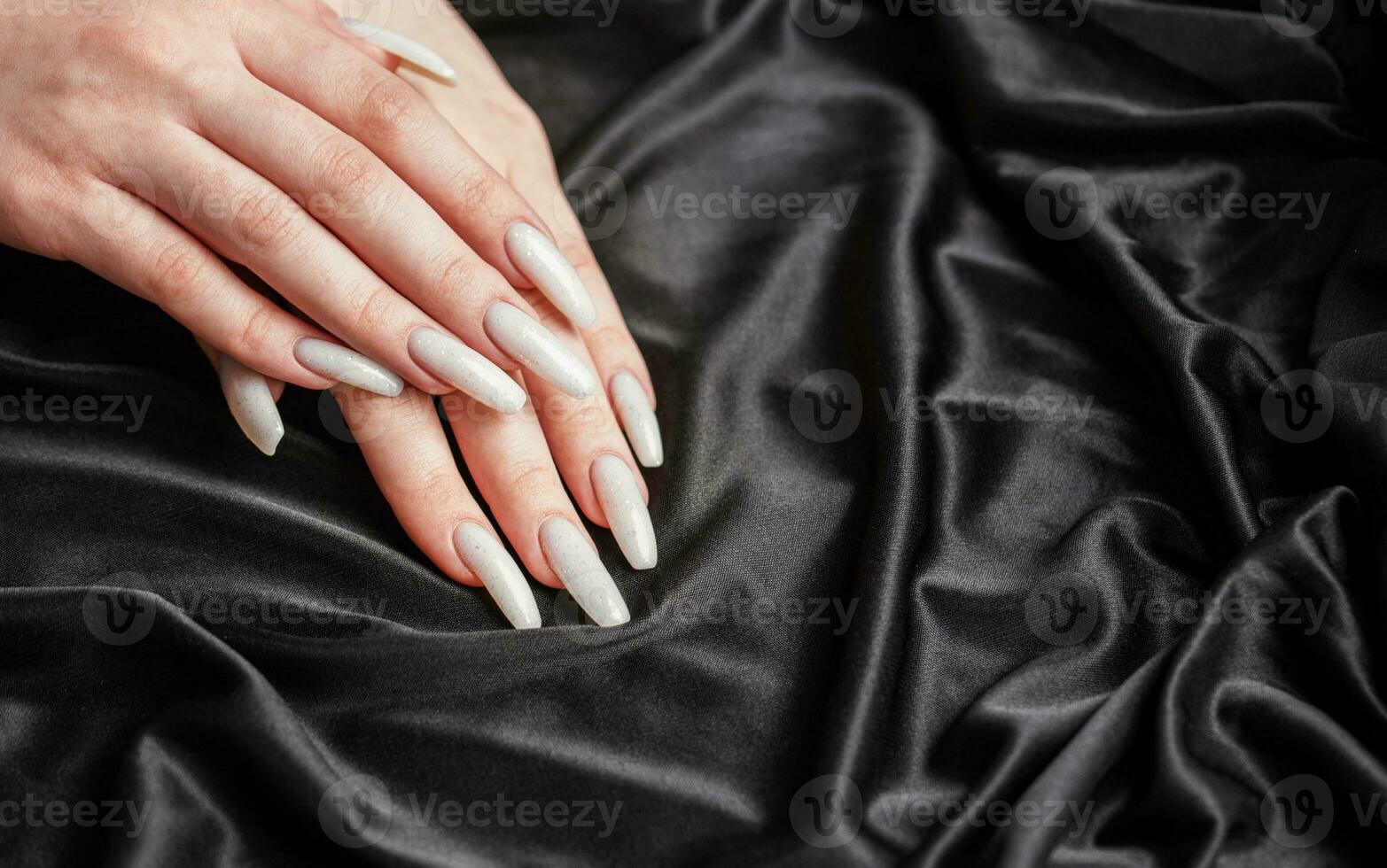 A woman's hands with a manicure on them, the nails are painted in a white color. photo