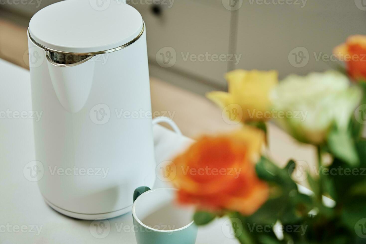Electric kettle and cup for tea on table photo