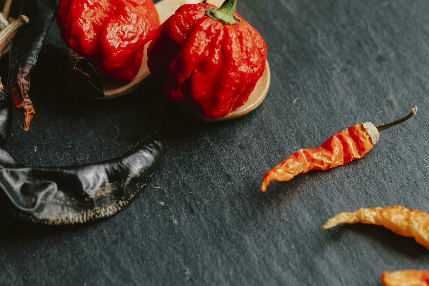 Hottest pepper in the world. Trinidad Scorpion Butch, thousands of times more spicy than Havana. On black slate background, with natural light. Spicy dark food food concept. photo