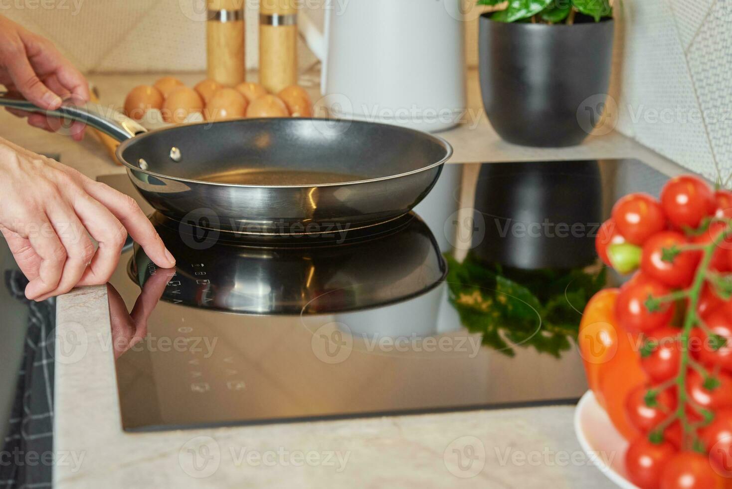 Woman turn on induction hob with frying pan photo