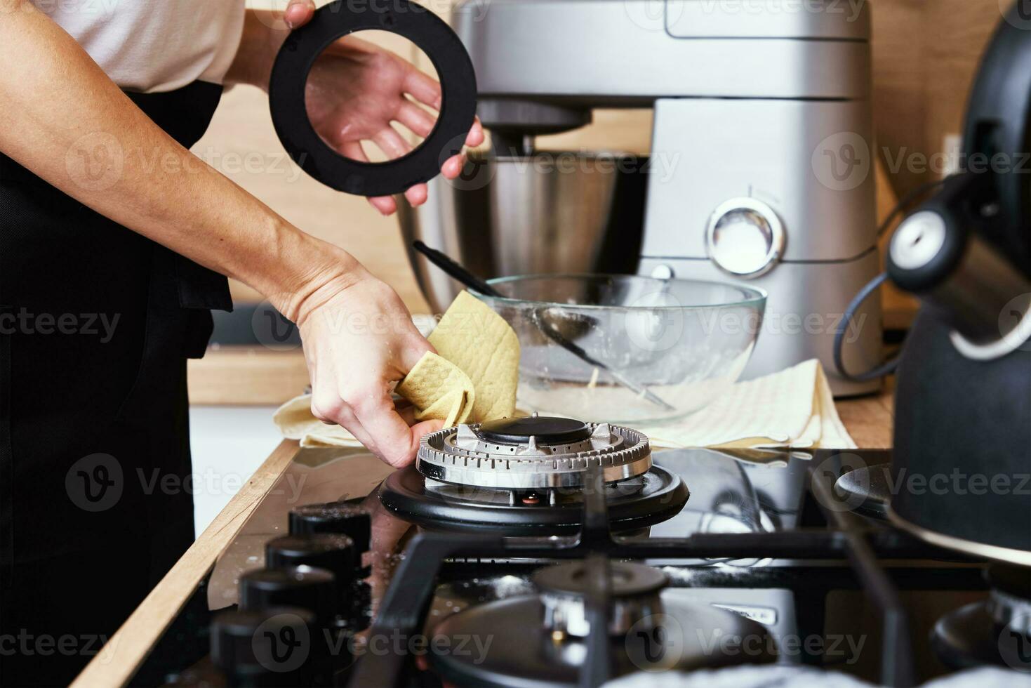 Woman cleaning gas stove in kitchen interior photo