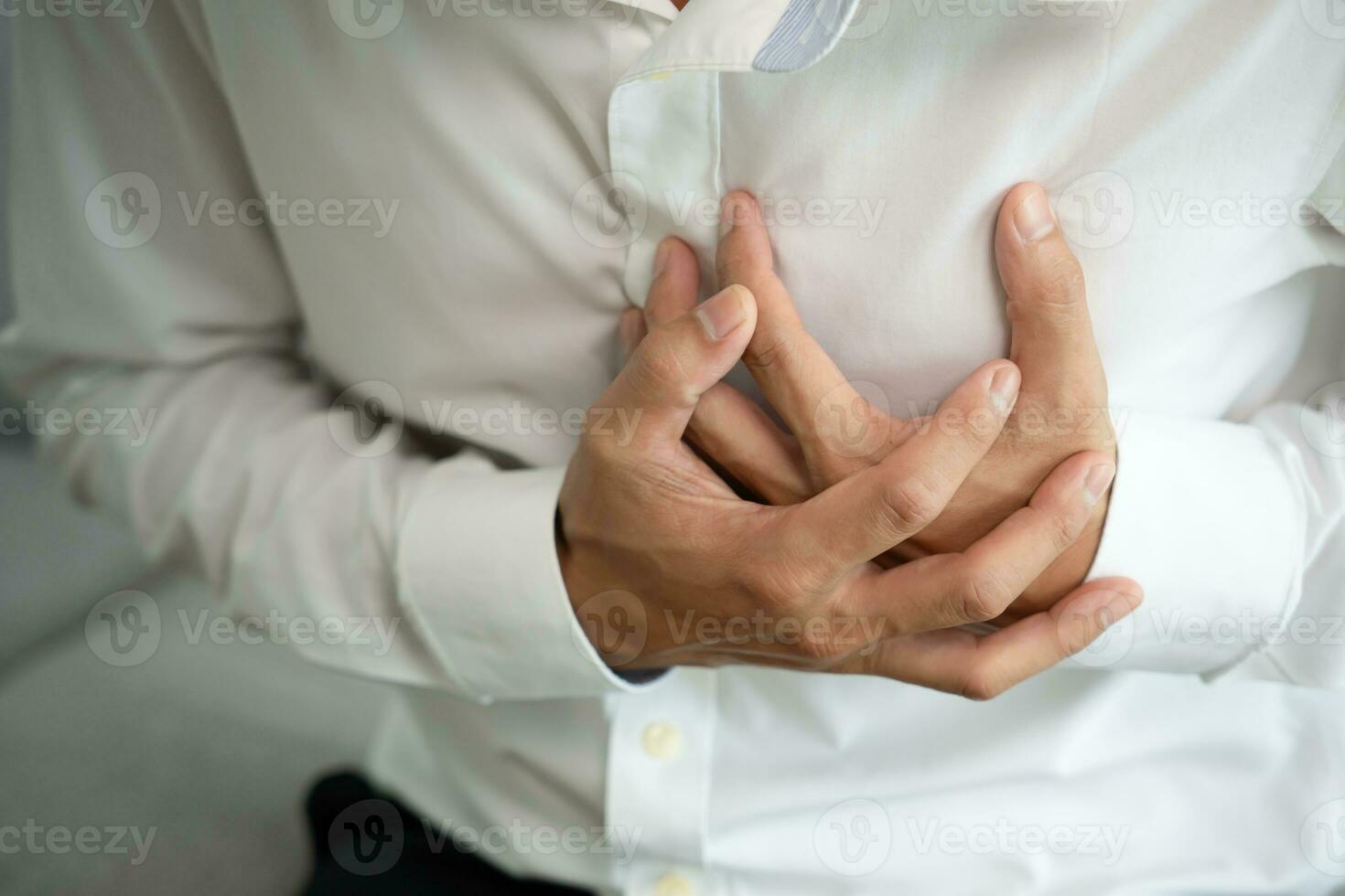 hand hold chest with heart attack symptoms, asian man working hard have chest pain caused by heart disease, leak, dilatation, enlarged coronary heart, press on the chest with a painful expression photo