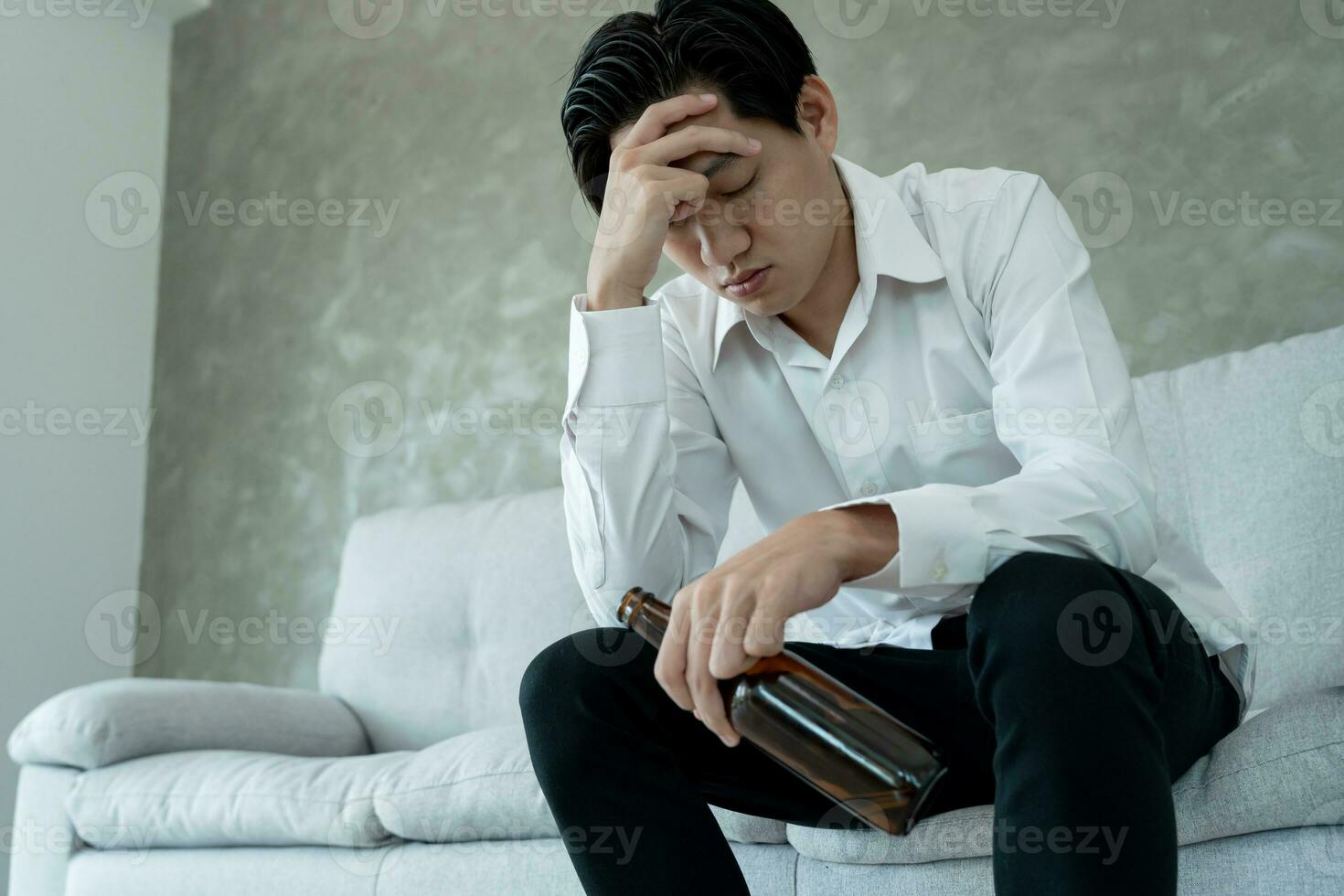 Depressed young business man addicted feeling bad drinking whiskey alone at home, stressed frustrated lonely drinking alcohol suffers from problematic liquor, alcoholism, life and family problems photo