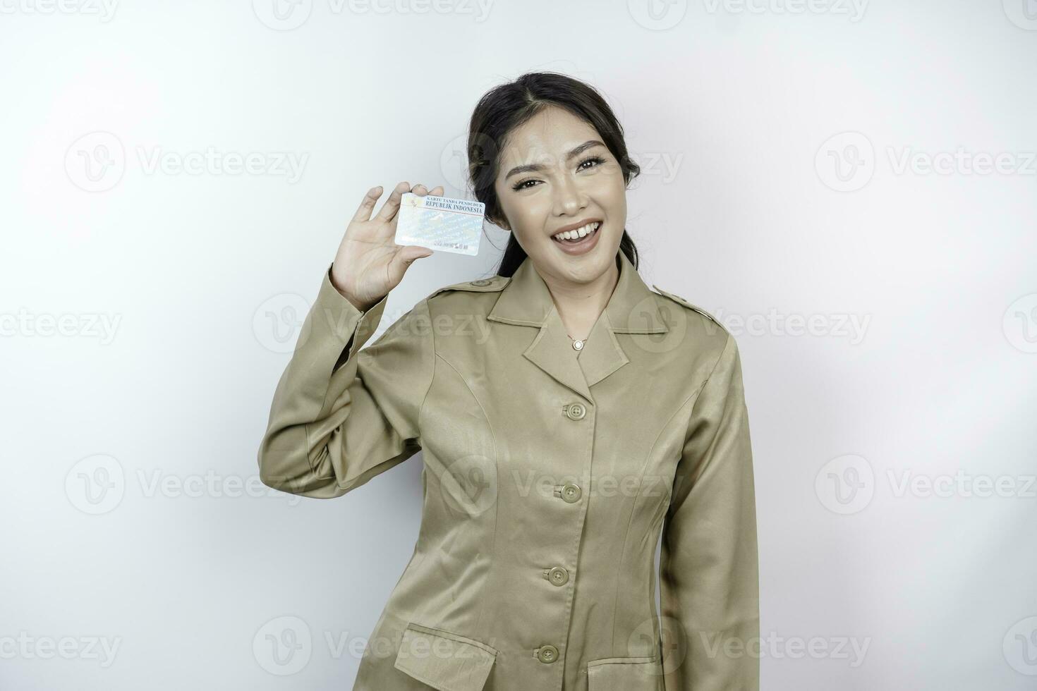 Smiling government worker woman holding Indonesian ID card. PNS wearing khaki uniform. photo