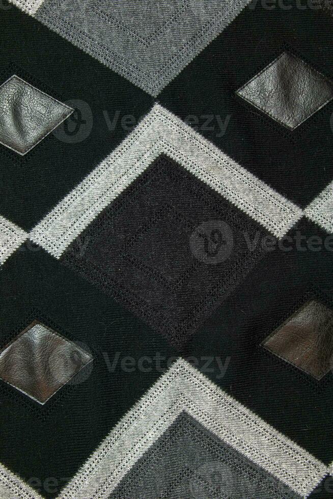 Detailed inserts in black genuine leather on a knitted woolen background with an abstract pattern. Abstract fabric texture. photo