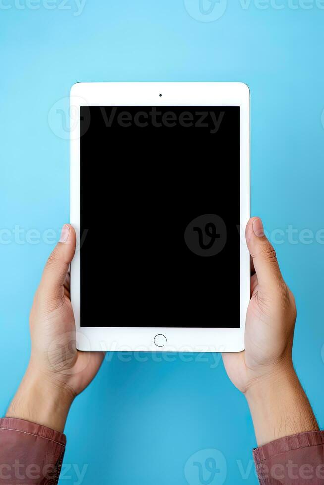 Hand holding tablet with mockup blank screen isolated on blue background. ai generated photo