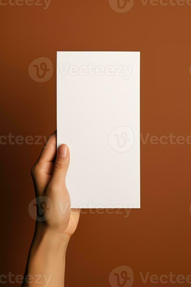 A human hand holding a blank sheet of white paper or card isolated on brown background. ai generated photo