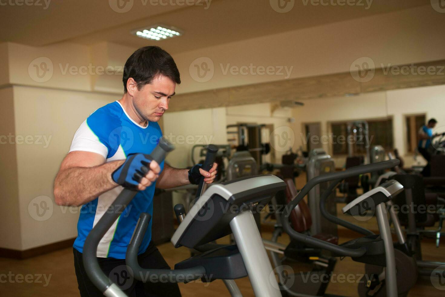 Man exercising on elliptical machine in gym photo