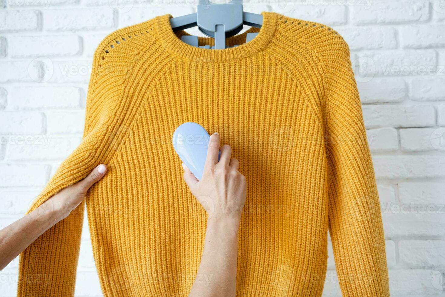 woman in yellow sweater using fabric pills removing tool photo