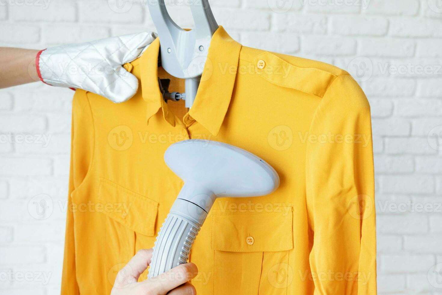 female hand using vertical steamer steaming clothes photo